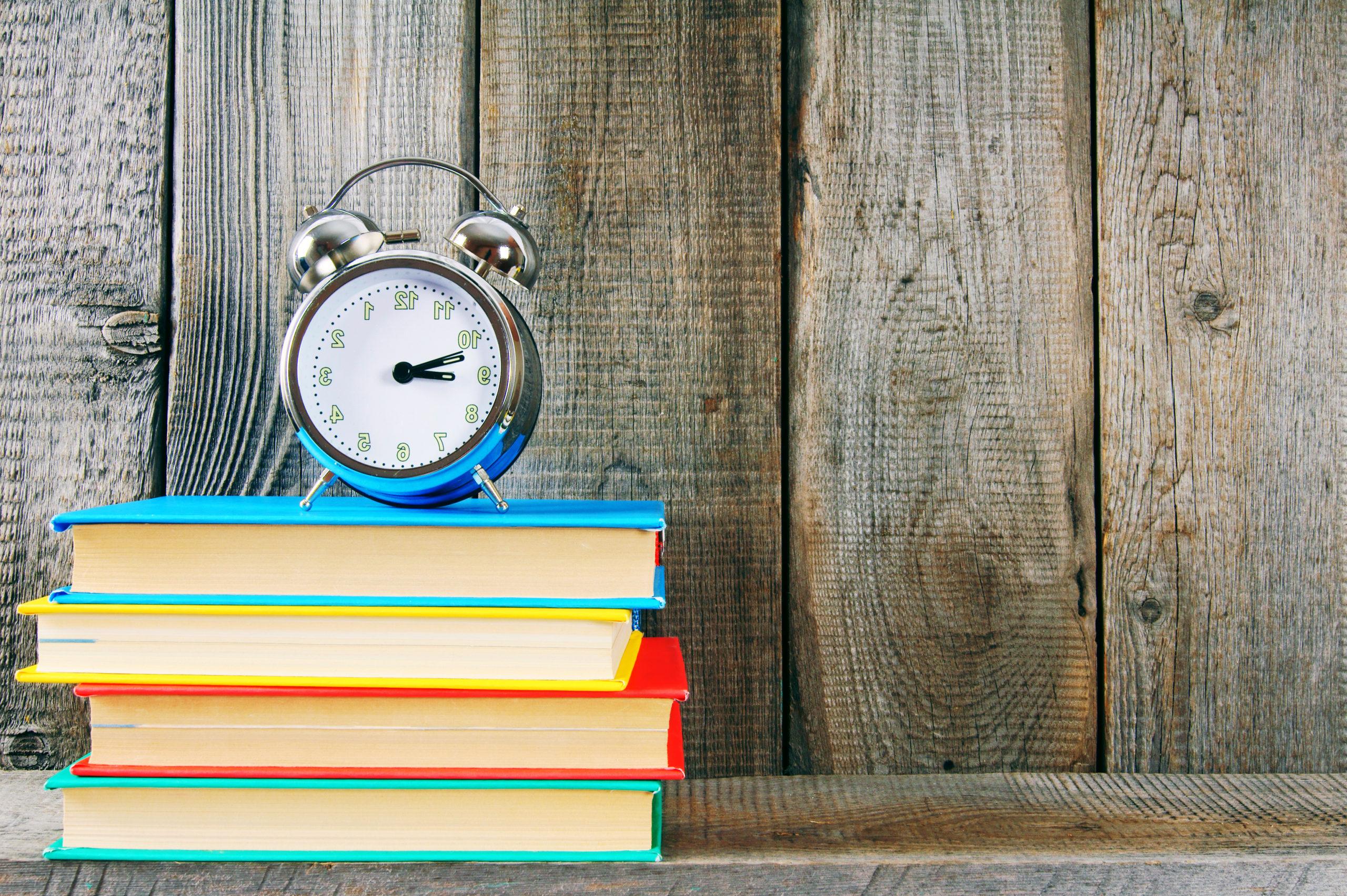An alarm clock sitting on top of a brightly colored stack of books