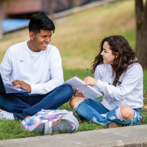 Two students sitting in the grass studying