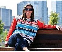 一个女人坐在校园的长椅上，穿着一件以市中心为背景的路跑者毛衣
