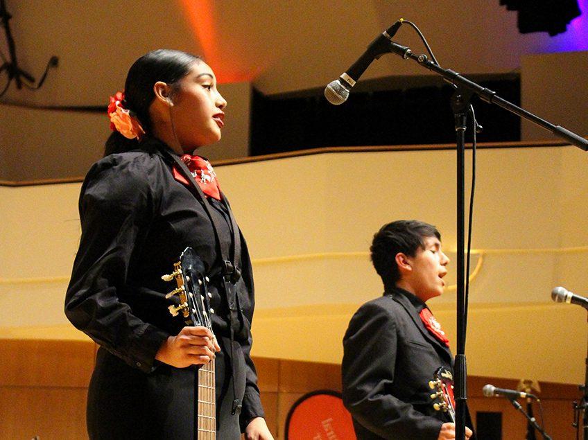 two mariachi singers performing onstage